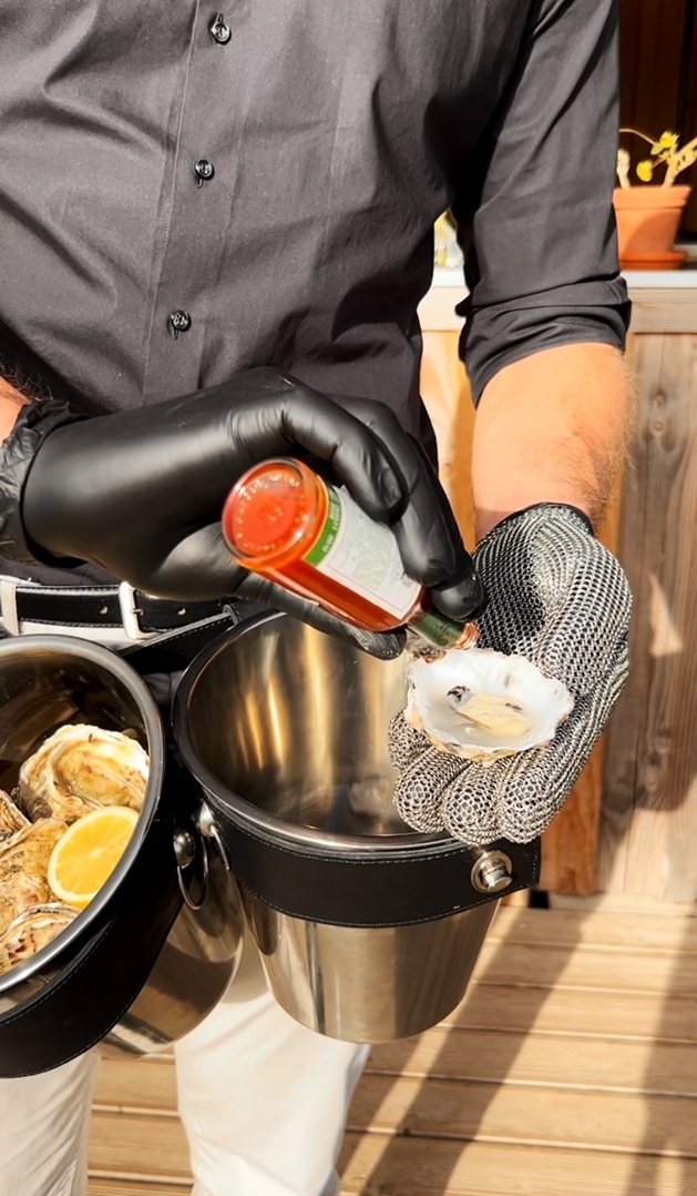 man pouring source on an oyster