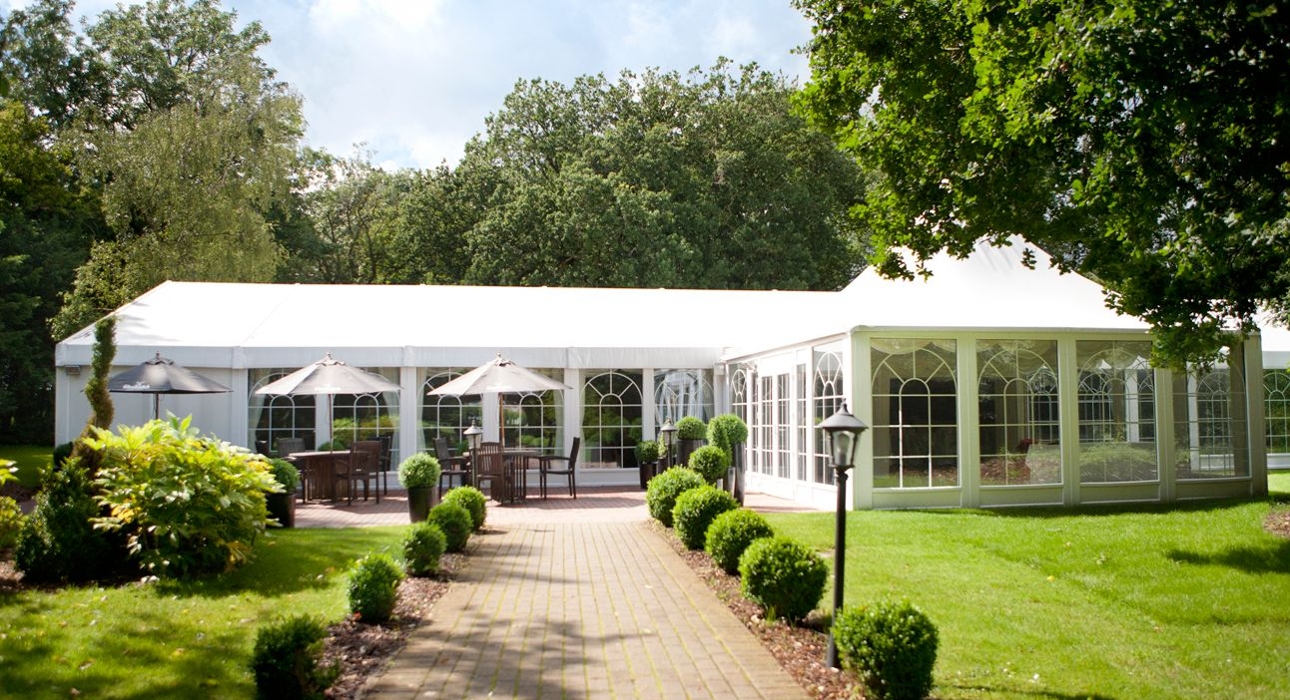 structured marquee in the ground of venue lots of trees