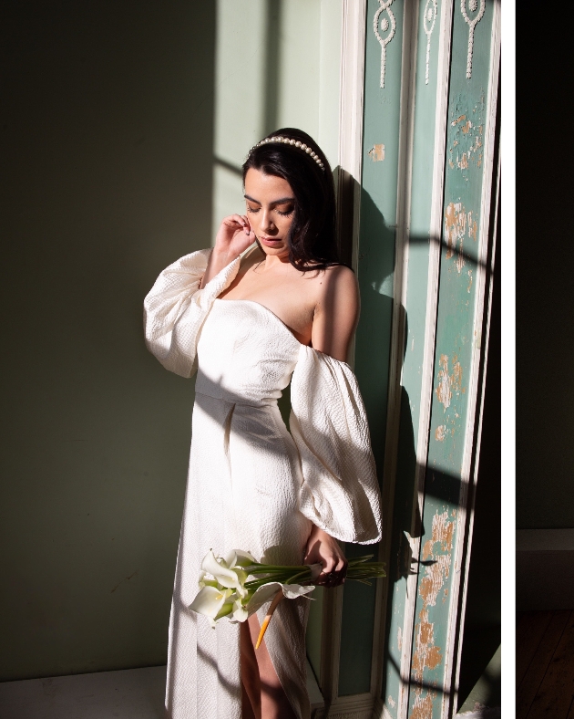 bride in dress standing in sunlight through a window