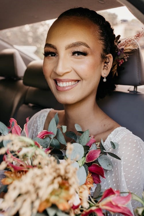 bride in car on wedding day holding flowers lovely make-up