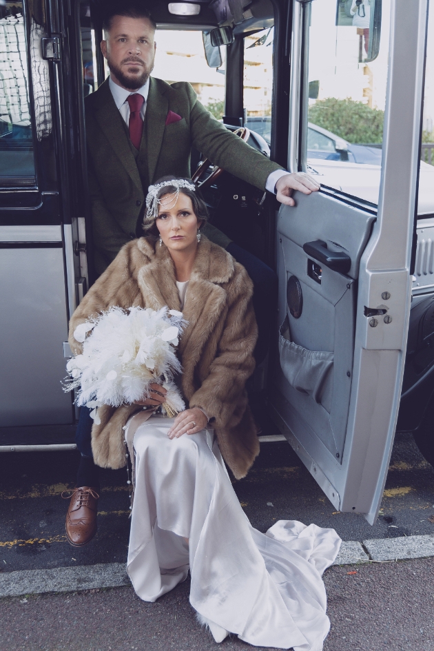 bride and groom vintage attire posing inside vintage wedding car