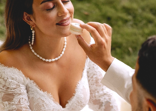 groom feeding a bride a macaron