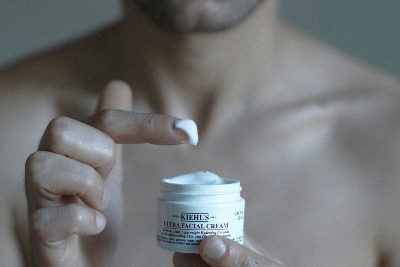 man dipping his finger in face cream