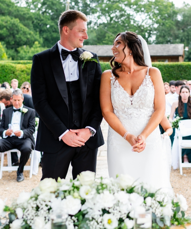 real wedding couple at altar on their big say surrounded by white flowers