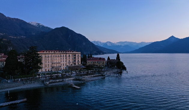 A large hotel on the lake surrounded by mountains